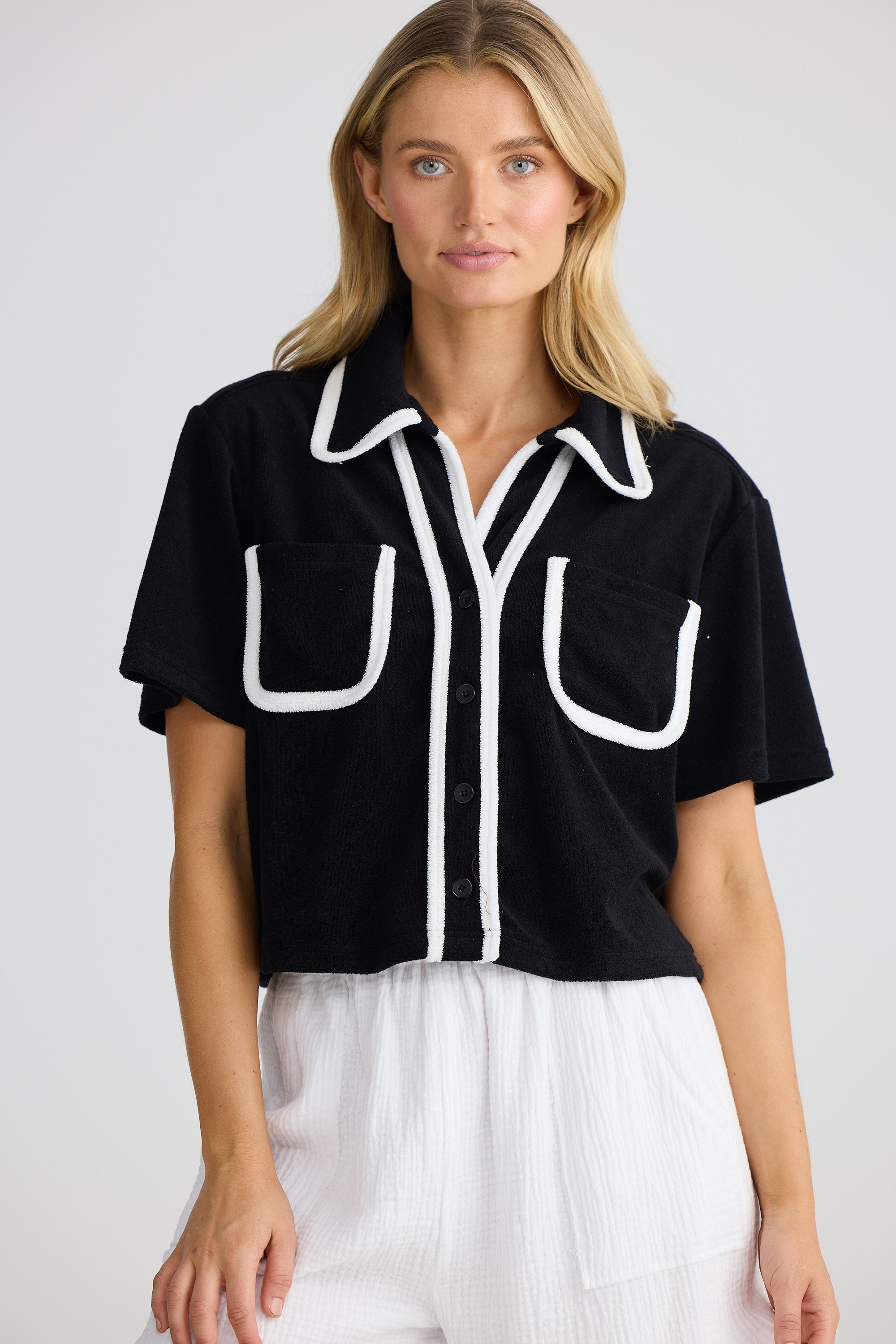 Woman wearing a black shirt with white accents on a plain background