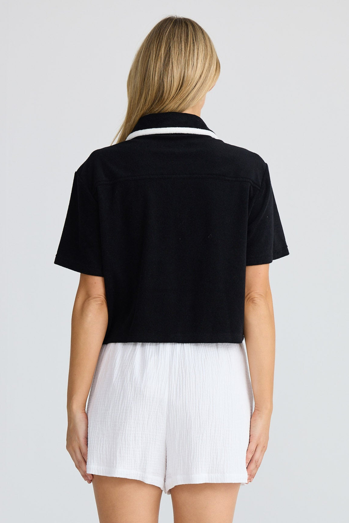 Person wearing a black shirt and white shorts on a plain background