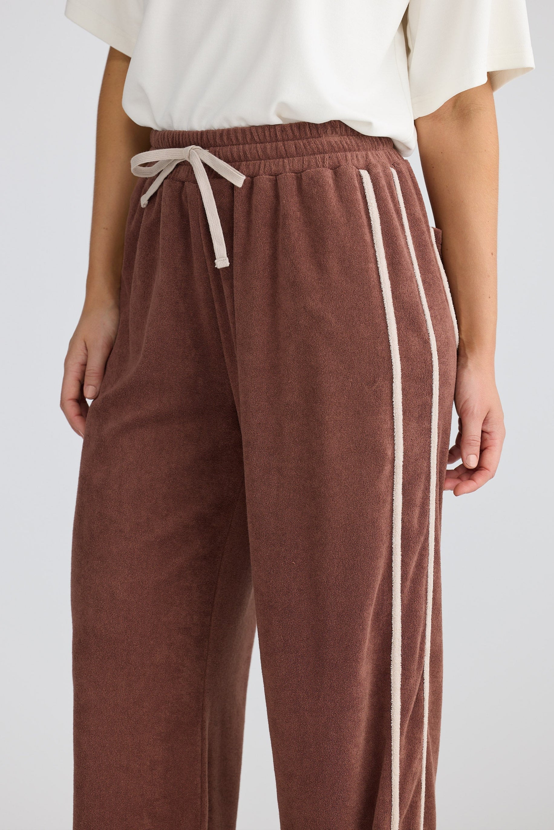 Brown sweatpants with white drawstring and stripes on a white background