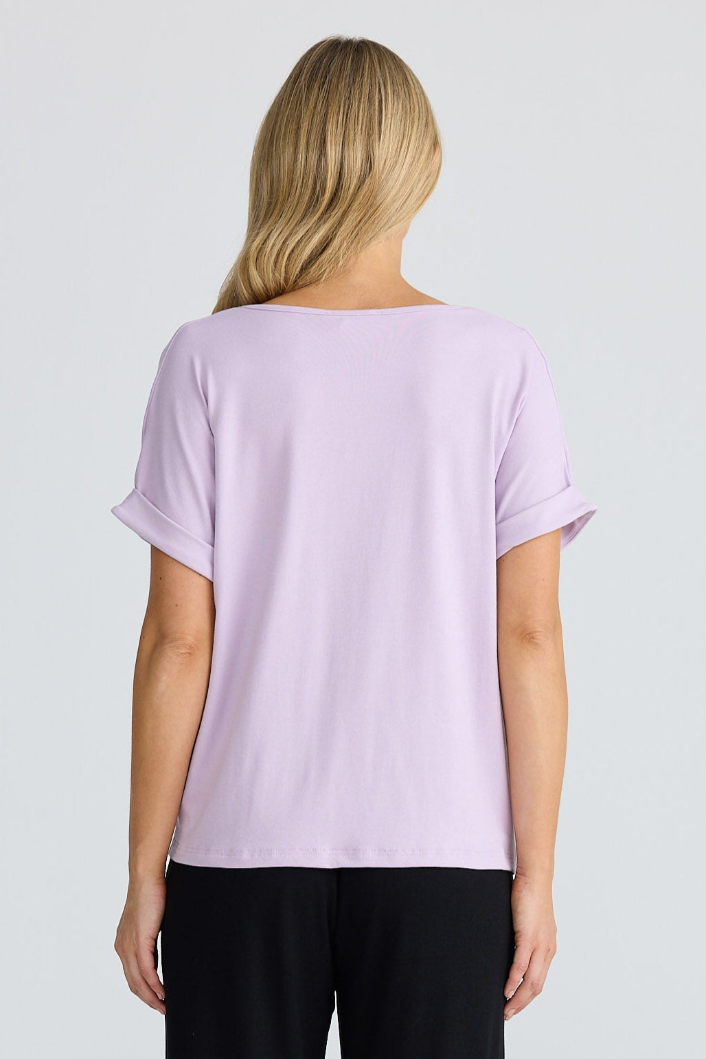 Person wearing a light purple t-shirt and black pants on a white background