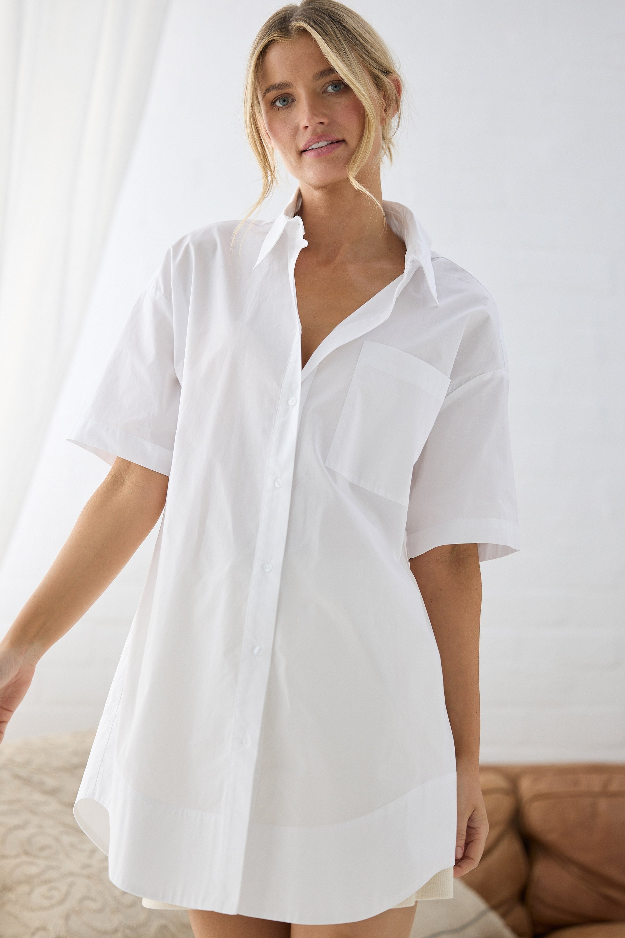 Woman wearing a white shirt dress against a neutral background
