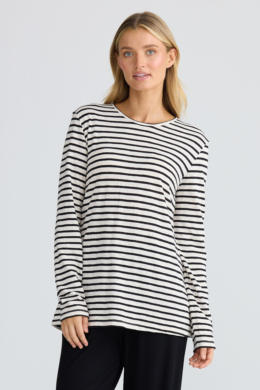 Woman wearing a black and white striped sweater and black pants on a white background