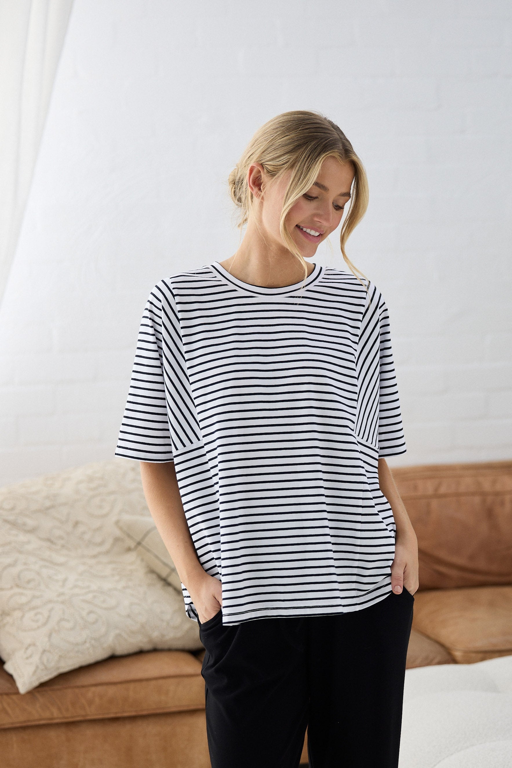 Woman wearing a black and white striped shirt and black pants in a living room.