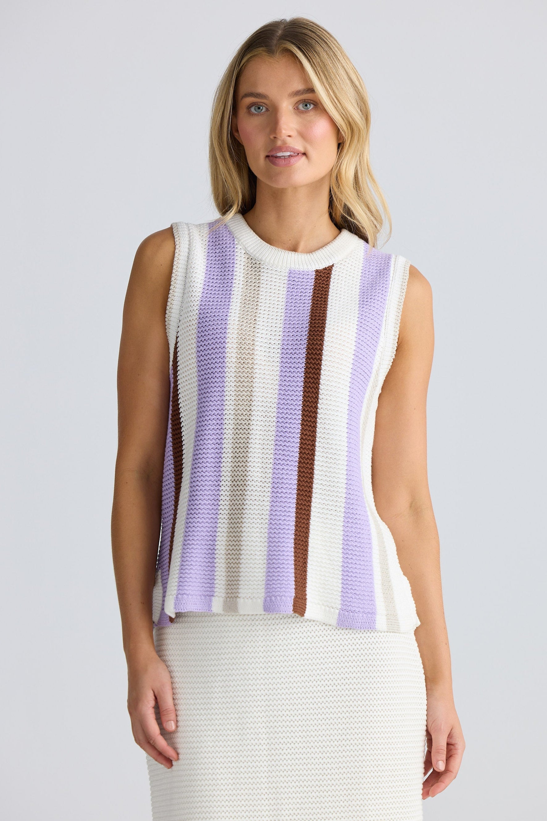 Woman wearing a sleeveless striped top with a plain background