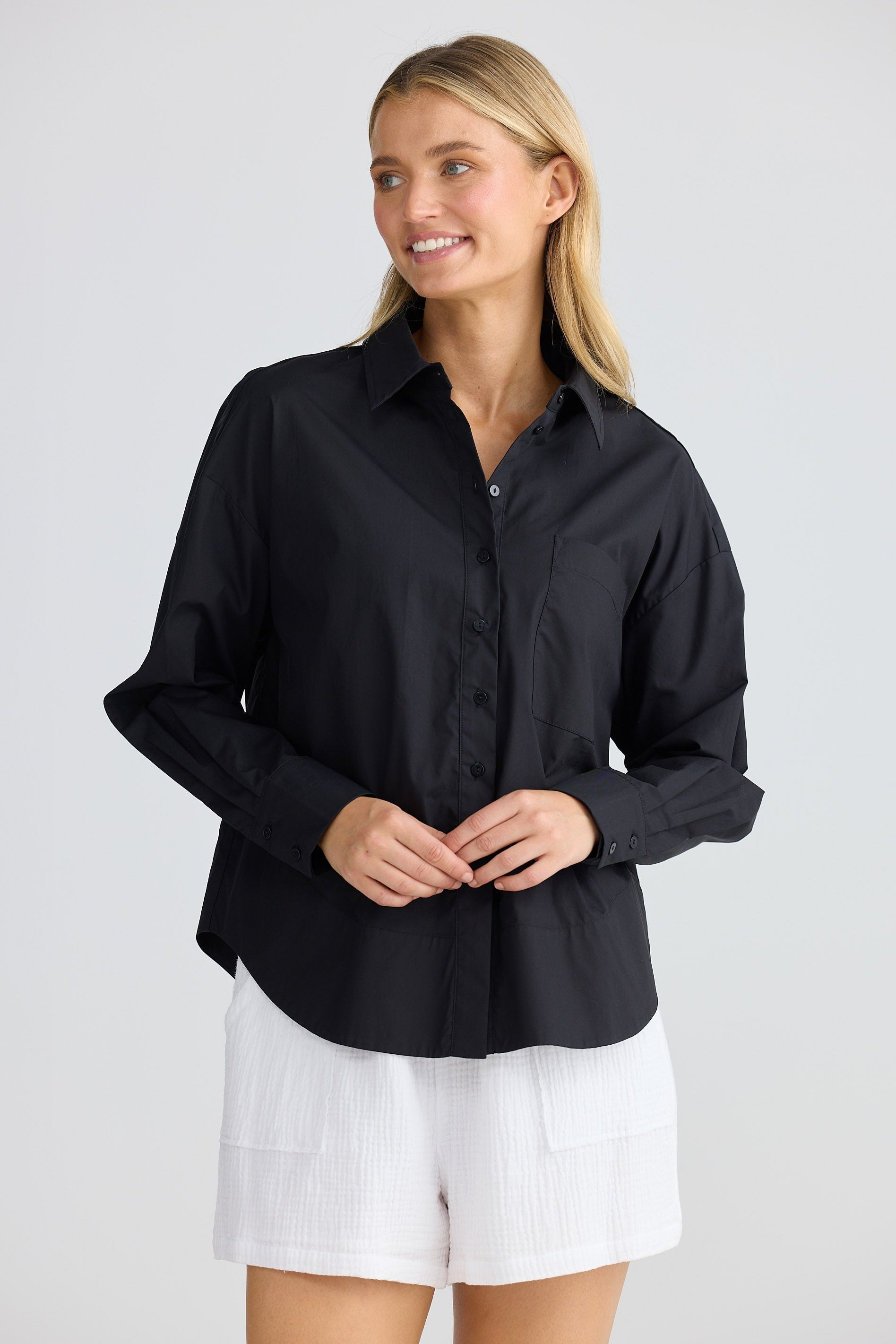 Woman wearing a black shirt and white shorts on a plain background