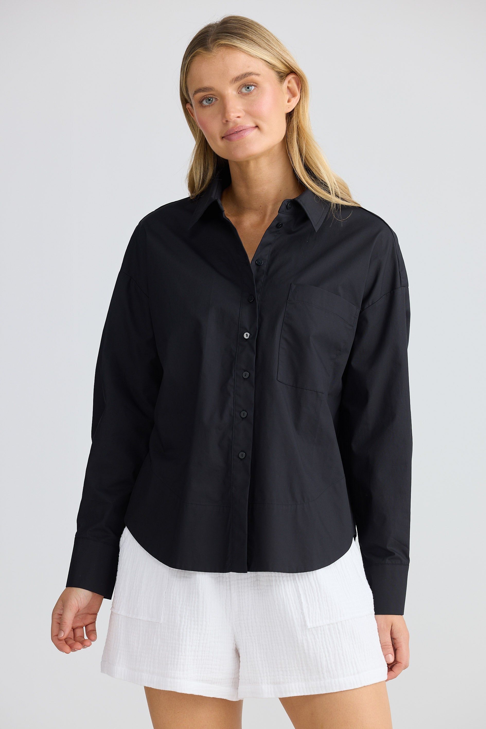 Woman wearing a black shirt and white shorts on a plain background