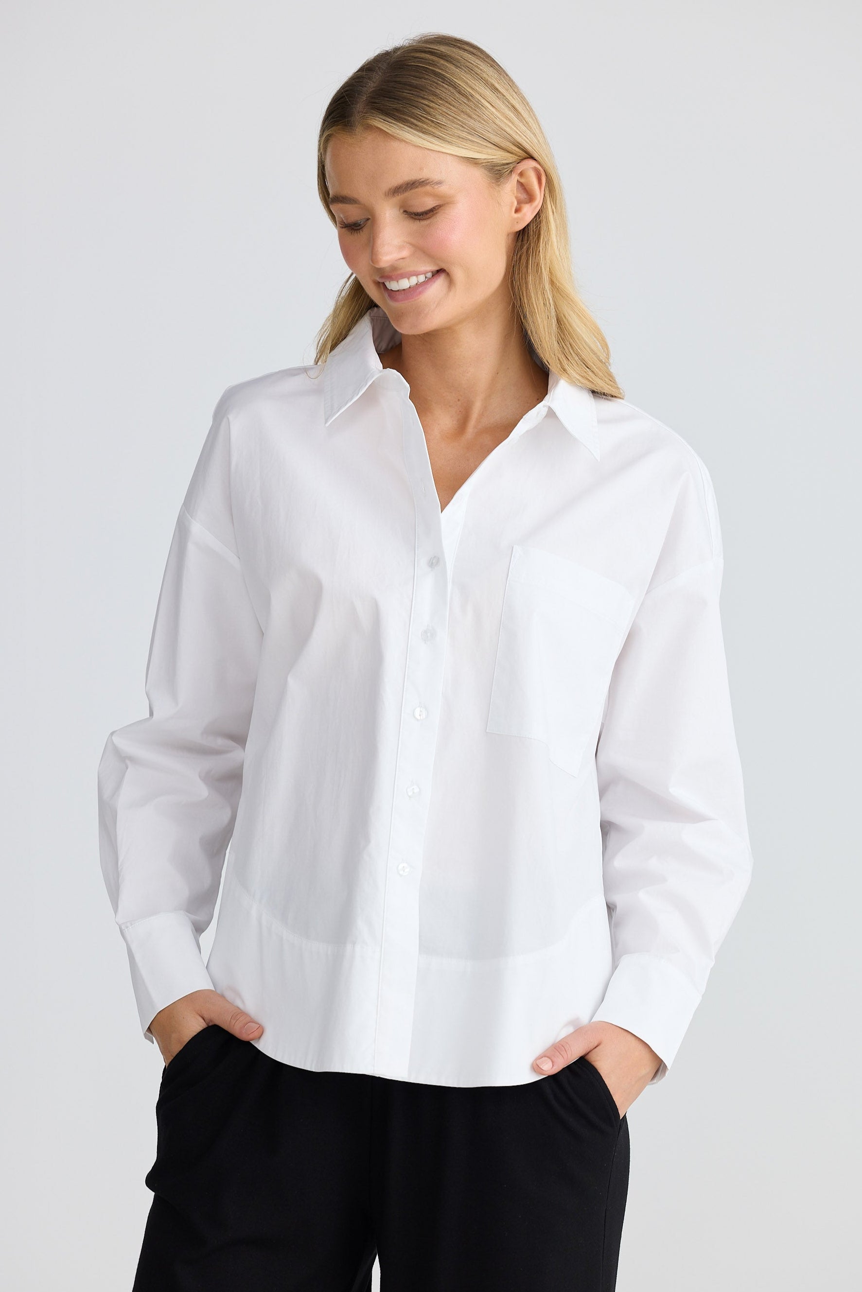 Woman wearing a white blouse and black pants on a light gray background