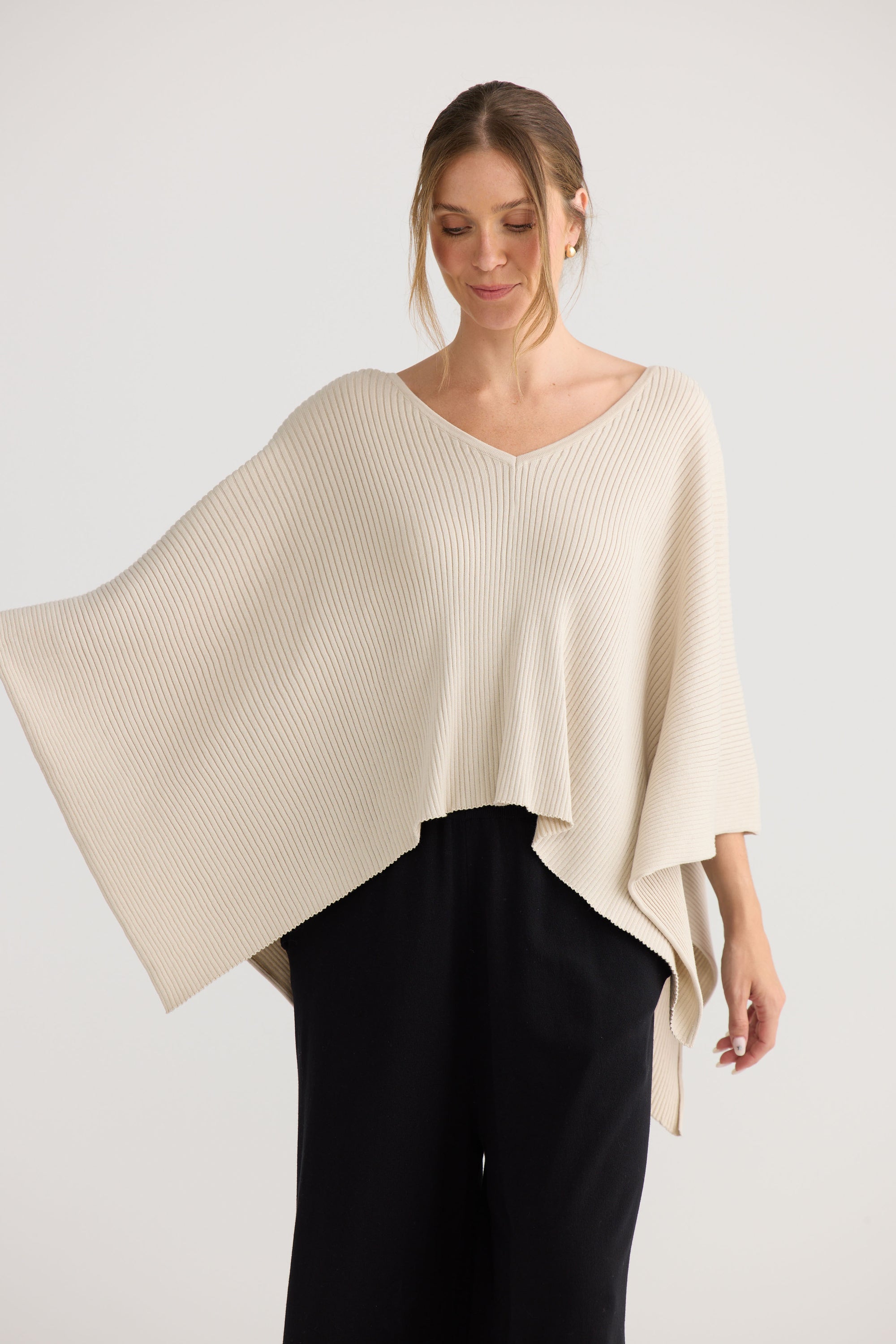 Model wearing Affirm Cape in cream, styled for everyday wear.