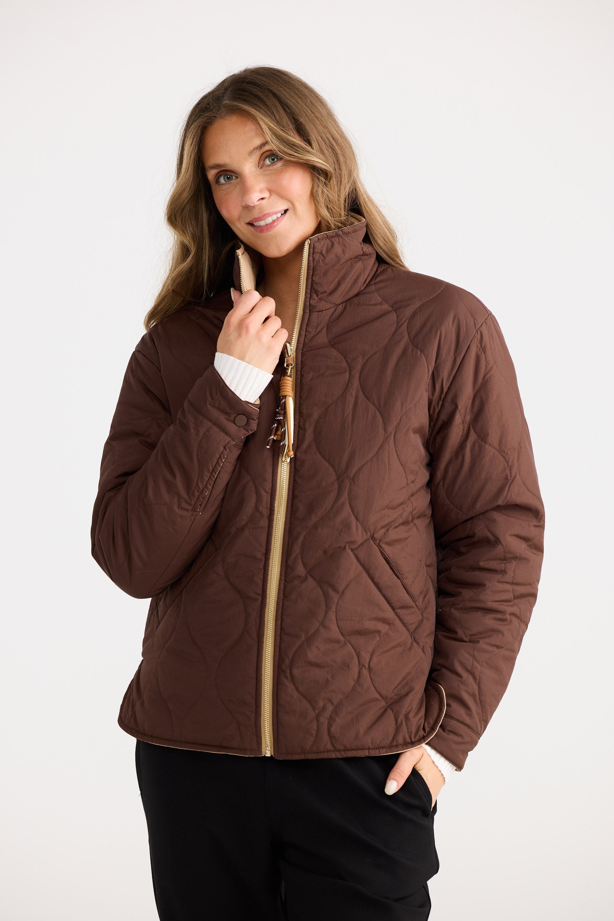 Woman wearing a brown quilted jacket on a white background