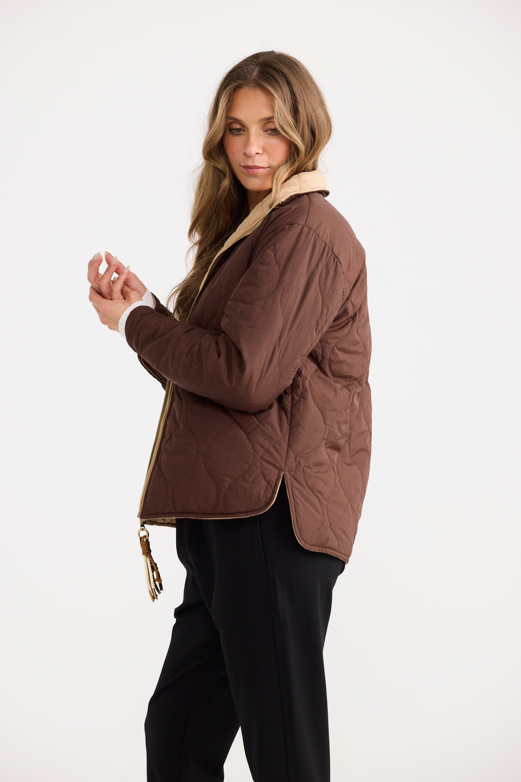 Woman wearing a brown quilted jacket on a white background