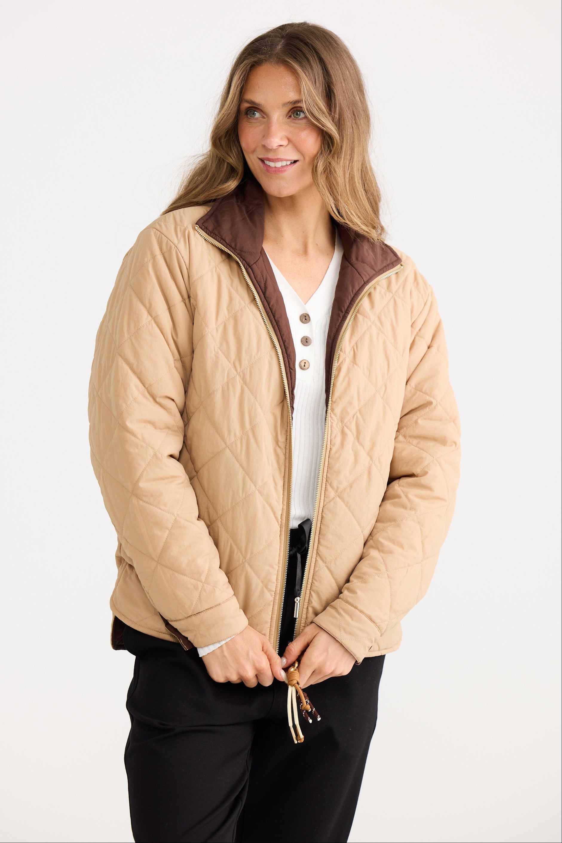 Woman wearing a beige quilted jacket on a white background