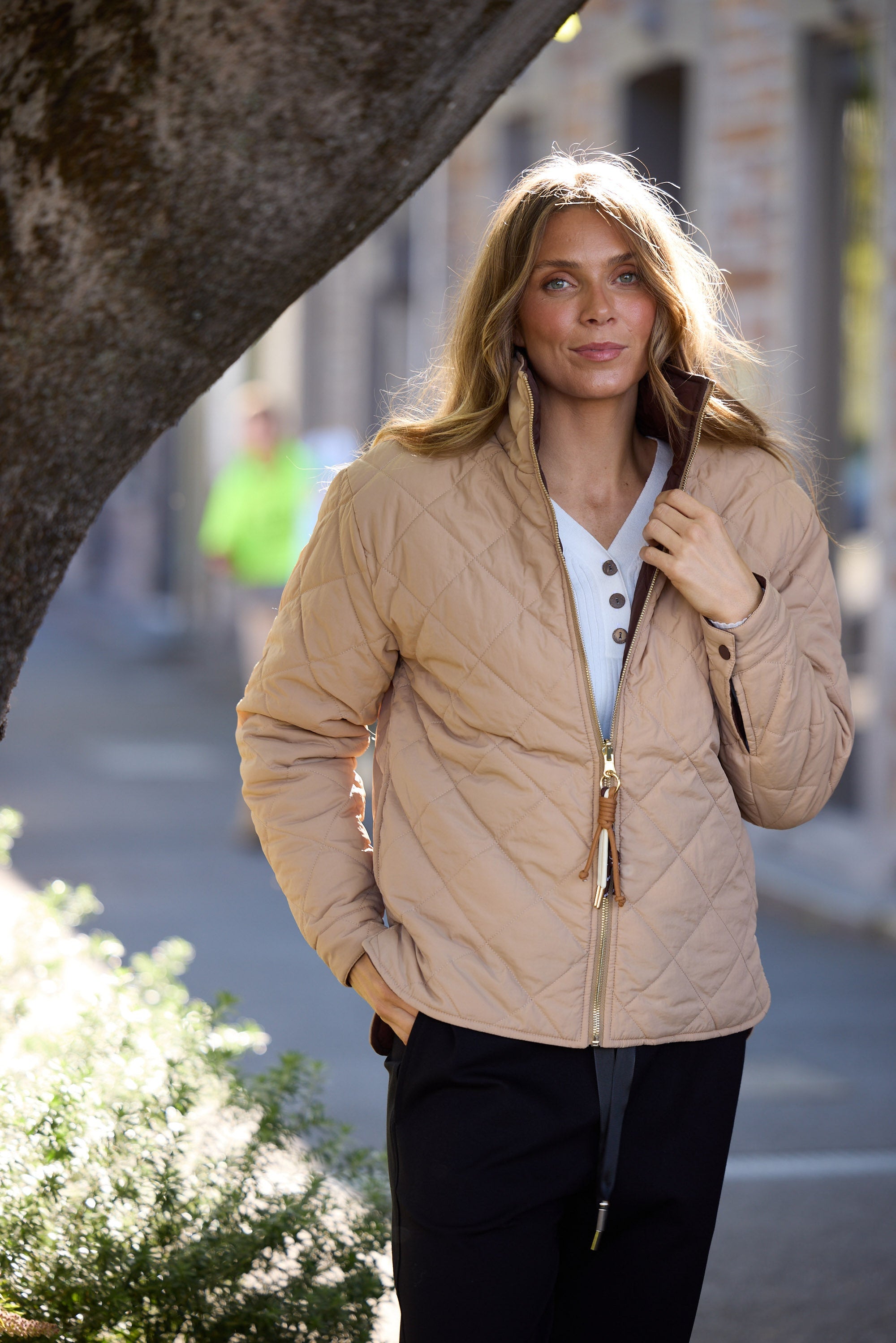 Woman wearing a beige quilted jacket on a city street