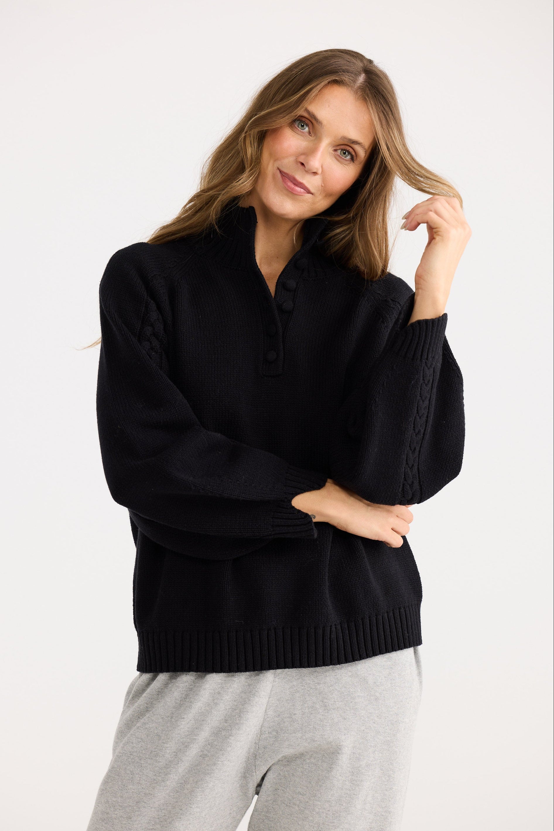 Woman wearing a black sweater and gray pants on a white background