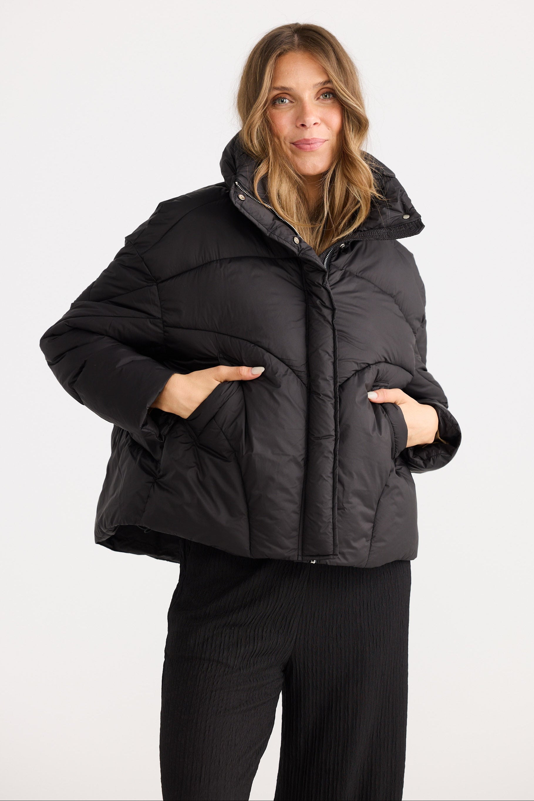 Woman wearing a black puffer jacket on a white background