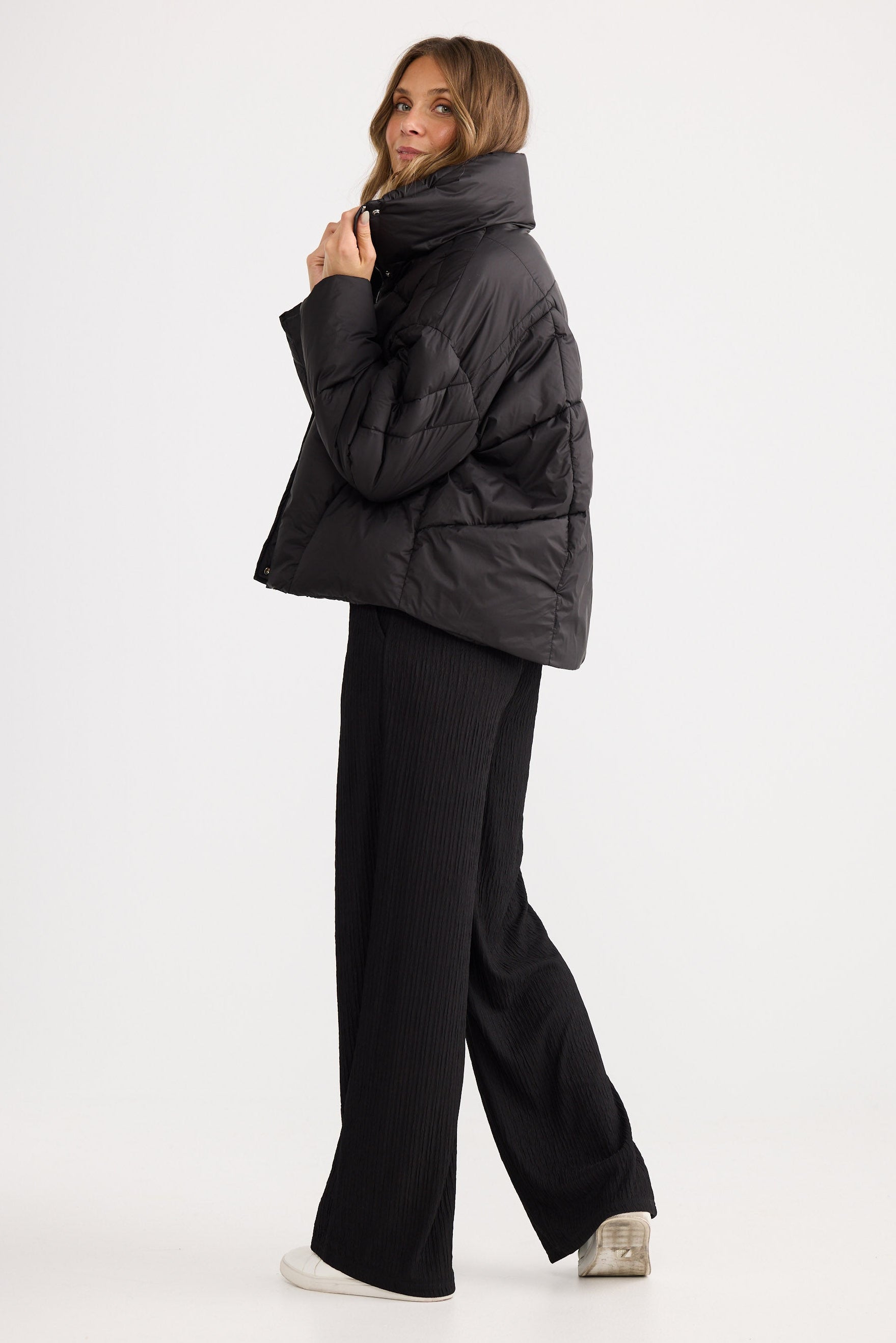 Woman wearing a black puffer jacket and pants on a white background
