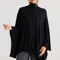 Model wearing Awaken Knit Cape in black, styled for everyday wear.
